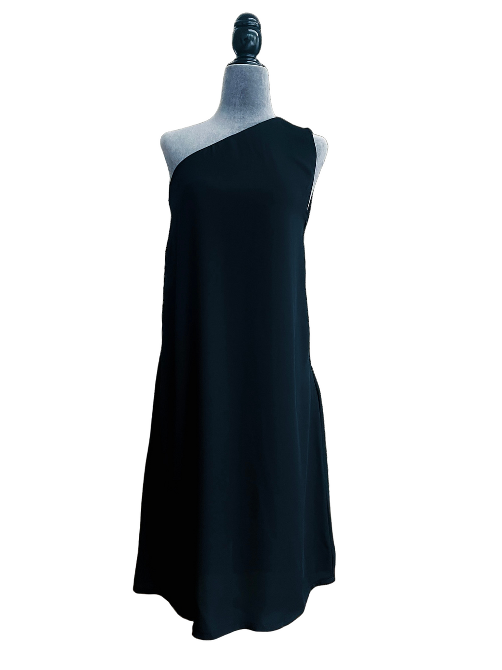 MØRKE Solveig Inner Dress — black one-shoulder knee-length dress with clean drape and side zip closure, shown on a mannequin. Minimalist viscose-crepe silhouette designed to be worn alone or layered under the Solveig overdress