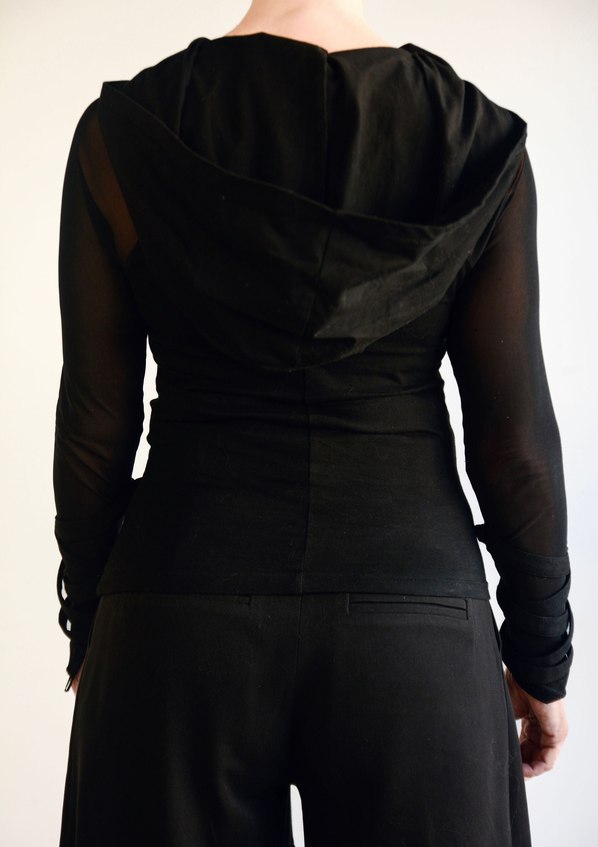 Black hooded outfit worn by a person on a plain background